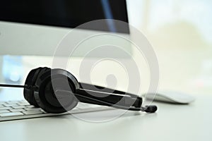 Headset on keyboard and monitor on desk at call center. Telemarketing, customer support service or sales