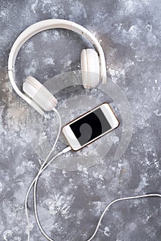 Headset and a phone on a stone background. Ready to listen to music.