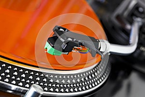 Headshell with cartridge over an orange vinyl