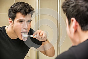 Headshot of attractive young man brushing teeth