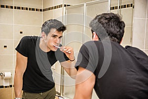 Headshot of attractive young man brushing teeth