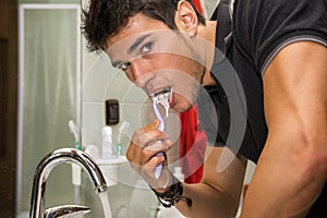 Headshot of attractive young man brushing teeth