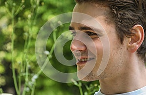 Headshot of attractive young man smiling in nature environment