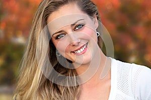 Headshot of a beautiful blonde woman outdoors, closeup smiling portrait, happy and cheerful