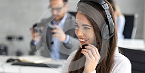 Headshot of beautiful young woman working in a call center. Friendly call center agent holding microphone while talking to