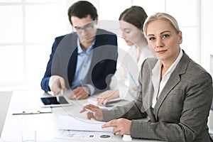 Headshot of business woman at negotiation. Group of business people discussing questions at meeting in modern office