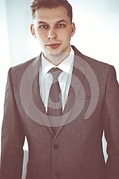 Headshot of businessman standing straight with colleagues at background in office. Group of business people discussing