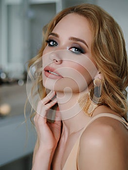 Headshot of happy beautiful blonde woman with gorgeous trendy makeup beauty shiny skin posing indoors with natural light