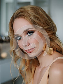 Headshot of happy beautiful blonde woman with gorgeous trendy makeup beauty shiny skin posing indoors with natural light