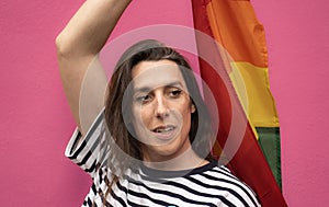 Headshot of a happy transgender woman holding a rainbow flag  on pin background