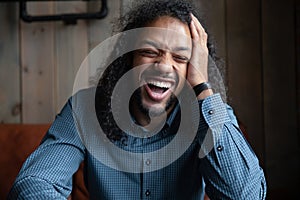 Headshot hilarious cheerful long-haired African guy laughing over joke