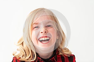 Headshot of a laughing young blonde preteen girl on a white studio background