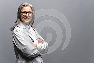 Headshot of mature female doctor , looking at the camera isolated on gray