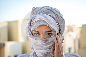 Headshot of Muslim girl dressed in traditional Arabic clothing outdoors.