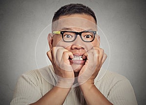 Headshot nerdy guy with glasses biting his nails looking anxious craving