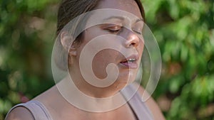 Headshot of perspiring plus-size sportswoman wiping sweat off face in slow motion looking away. Close-up portrait of