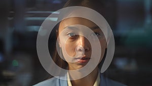 Headshot portrait of Asian woman behind glass with blinders closing. Front view close-up of young female employee