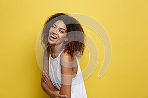 Headshot portrait of beautiful attractive African American woman posting crossed arms with happy smiling. Yellow studio