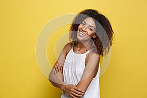 Headshot portrait of beautiful attractive African American woman posting crossed arms with happy smiling. Yellow studio