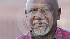 Headshot portrait of citizen serious pensive black male with wrinkles looking at camera closeup, friendly grandfather