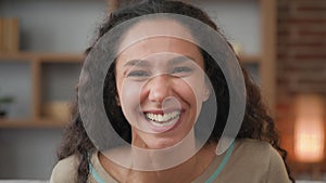 Headshot portrait closeup indoors happy female face cheerful Hispanic woman with curly hair feels good mood happy laughs