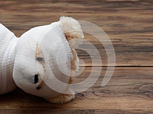 Headshot portrait of cute mummy teddy bear doll bind with white gauze or bandage on dark wooden background