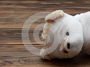 Headshot portrait of cute mummy teddy bear doll bind with white gauze or bandage on dark wooden background