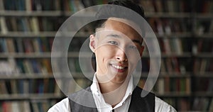 Headshot portrait of handsome Asian guy student pose in library