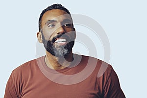 headshot portrait of a handsome bearded mid adult man smiling looking away at copy space against gray background