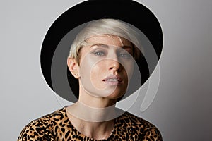 Headshot Portrait of happy blonde girl with black hat smiling looking at camera. White background