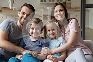 Headshot portrait of happy family with kids relaxing on couch