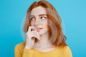 Headshot Portrait of happy ginger red hair girl with freckles smiling looking at camera. Pastel blue background. Copy