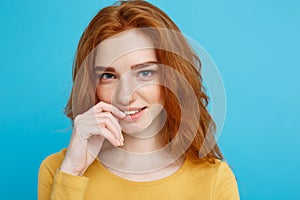 Headshot Portrait of happy ginger red hair girl with freckles smiling looking at camera. Pastel blue background. Copy