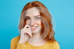 Headshot Portrait of happy ginger red hair girl with freckles smiling looking at camera. Pastel blue background. Copy