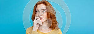 Headshot Portrait of happy ginger red hair girl with freckles smiling looking at camera. Pastel blue background. Copy