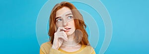 Headshot Portrait of happy ginger red hair girl with freckles smiling looking at camera. Pastel blue background. Copy