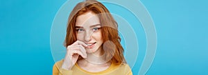 Headshot Portrait of happy ginger red hair girl with freckles smiling looking at camera. Pastel blue background. Copy