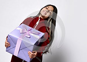 Caucasian preteen girl in tracksuit holding wrapped gift box portrait