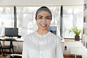 Headshot portrait of indian female employee posing in office