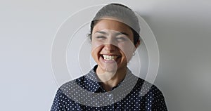 Headshot portrait Indian woman laughing standing on grey studio background