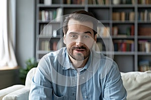 Headshot portrait millennial guy sit on sofa makes video call