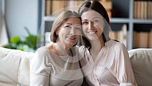 Headshot portrait of senior mother and adult daughter on couch