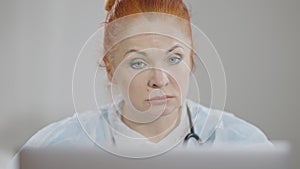 Headshot portrait of serious professional female doctor consulting using video chat on laptop. Close-up of concentrated