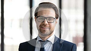 Headshot portrait of smiling businessman in glasses at workplace