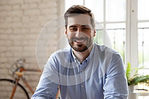 Headshot portrait of smiling Caucasian male employee posing in office