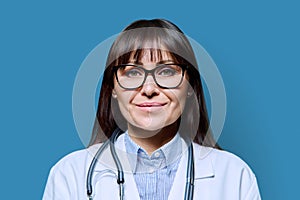 Headshot portrait smiling female doctor looking at camera on blue background