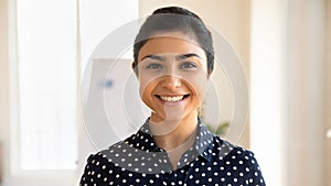 Headshot portrait of smiling indian female employee pose in office