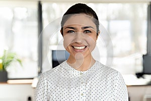 Headshot portrait of smiling indian female employee posing