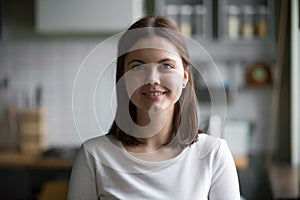 Headshot portrait of smiling millennial woman posing at home kit