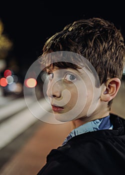 headshot portrait of a young boy lost at night looking back scared